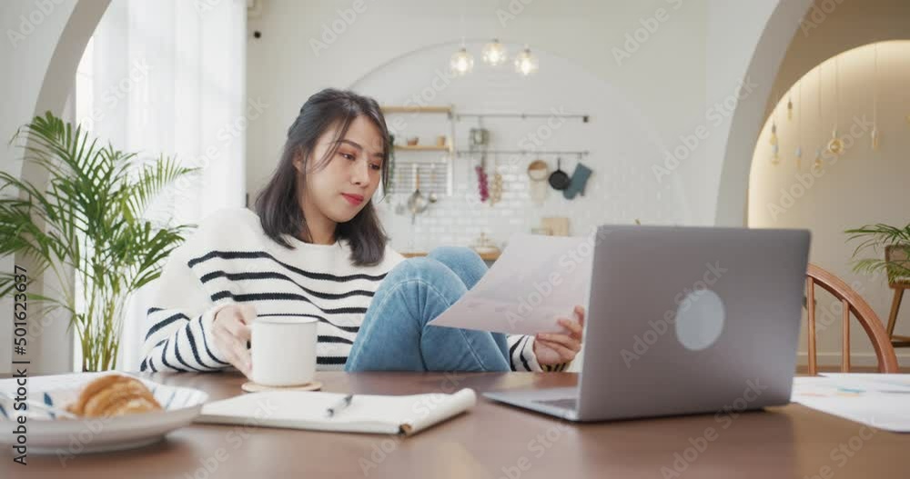 Freelance Asia lady casual wear using laptop and drink coffee in kitchen at house. Working from home, remotely work, distance education, social distancing, quarantine for coronavirus prevention. Freelance Asia lady casual wear using laptop and drink coffee in kitchen at house. Working from home, remotely work, distance education, social distancing, quarantine for coronavirus prevention.
