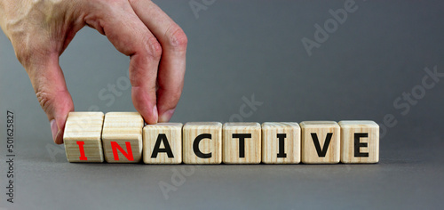 Active or inactive symbol. Businessman turns wooden cubes and changes the word Inactive to Active. Beautiful grey table grey background, copy space. Business and active or inactive concept.
