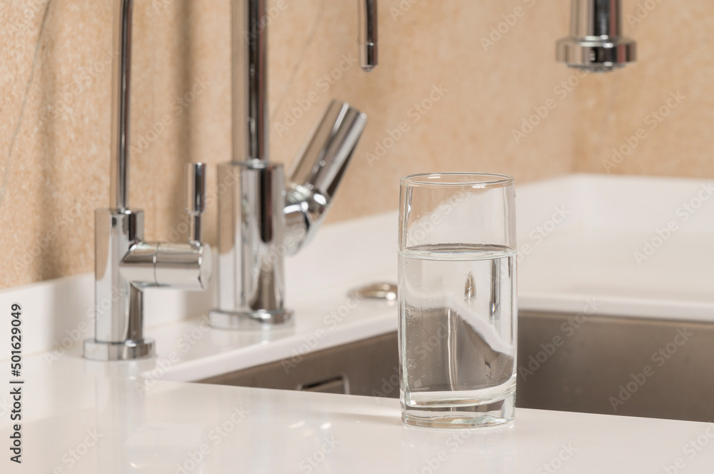 a glass of clean transparent drinking water stands on the kitchen table a glass of clean transparent drinking water stands on the kitchen table