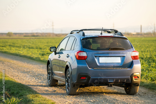 Landscape with blue off road car on gravel road. Traveling by auto, adventure in wildlife, expedition or extreme travel on a SUV automobile. Offroad 4x4 vehicle in field at sunrise. © bilanol