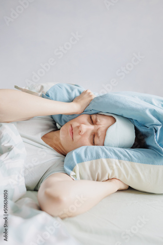 woman lies in bed and yawns or sleeps with a sleeping mask on her face. a European woman with sleep problems and insomnia, waking up and falling asleep in a cozy house. sleep disorders or depression
