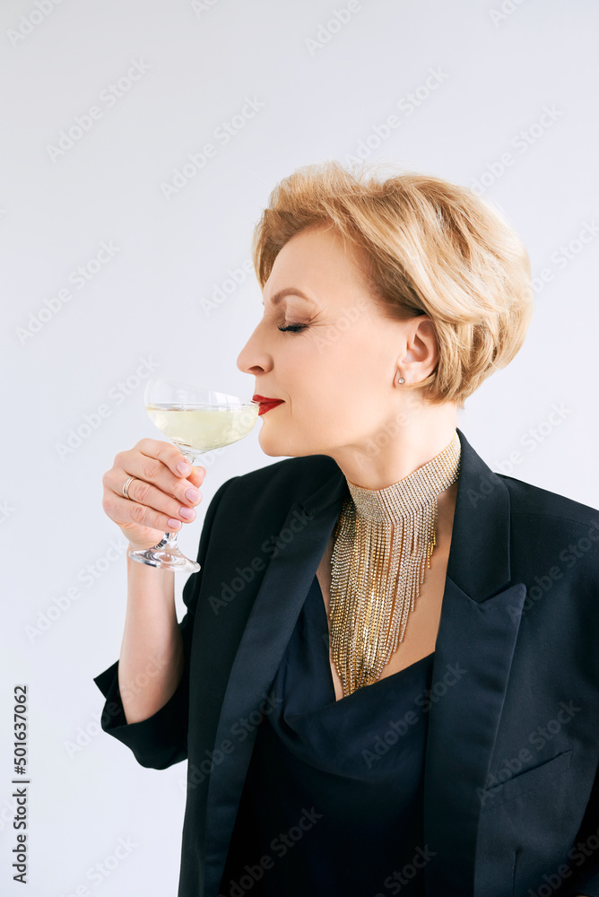 mature stylish elegant woman in tuxedo with glass of sparkling wine. Party, celebration, anti age concept mature stylish elegant woman in tuxedo with glass of sparkling wine. Party, celebration, anti age concept