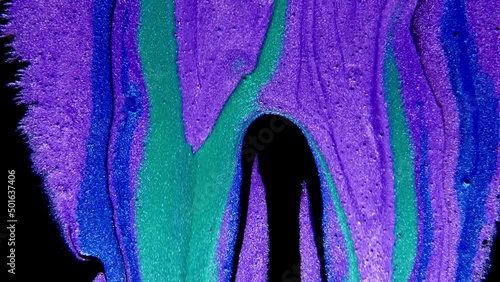 Abstract paint mixing neon blue green and violet purple colors ink. Liquid colorful amazing organic background.