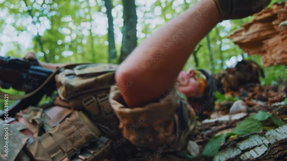 Close up the soldier hiding gives himself first aid and puts on a tourniquet on wounded leg. Healthcare. Training in forest Close up the soldier hiding gives himself first aid and puts on a tourniquet on wounded leg. Healthcare. Training in forest