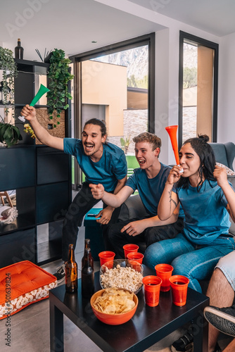 friends of championship fans shouting for joy after their team's victory, watching the broadcast on television.