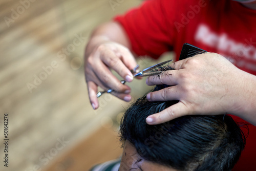 Hands of a fat barber cutting the hair of a client using scissors © DavidMorillo