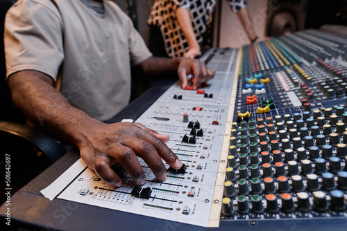 Unrecognizable audio engineer and musician creating track using mixer in recording studio