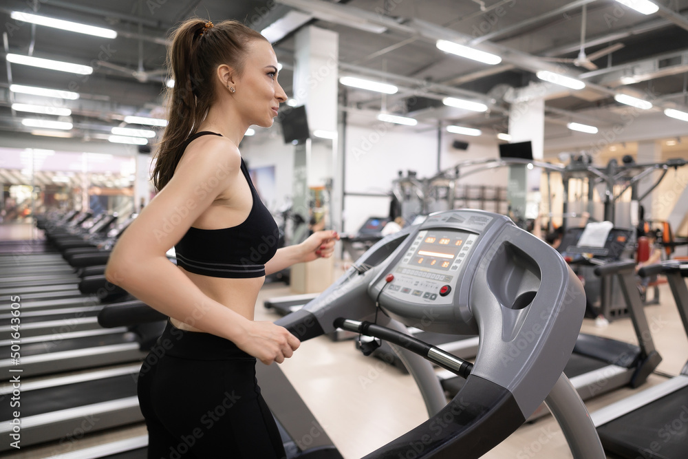 Fototapeta premium Adult woman running on treadmill