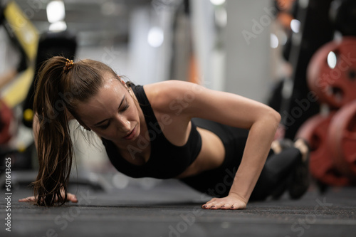 Woman trains in the gym, doing push-ups from the floor