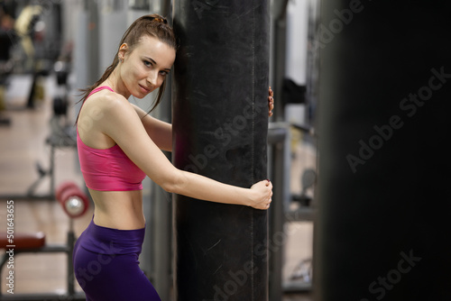 Female boxer poses near a large punching bag