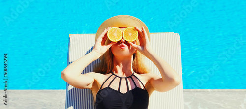 Foto Summer portrait of woman covering her eyes with fresh slices of orange lying on