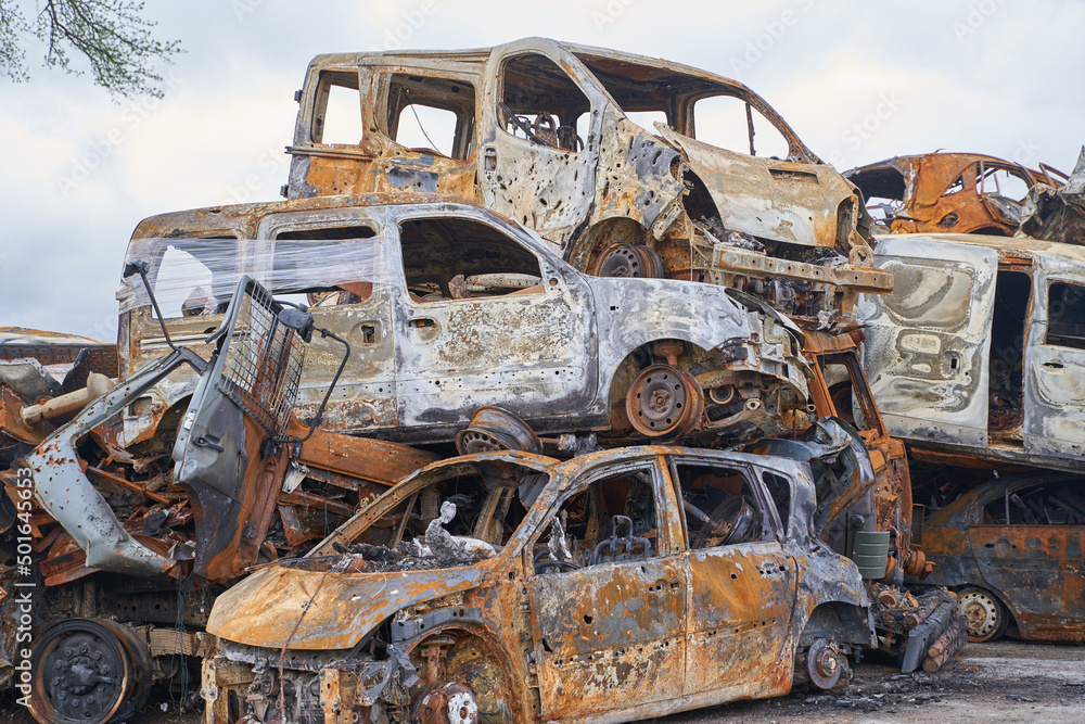 Fototapeta premium 2022 Russian invasion of Ukraine war. War ruins city damage car. Terror attack bomb shell of civilian bombed. Disaster area. cars beaten by shrapnel and burnt
