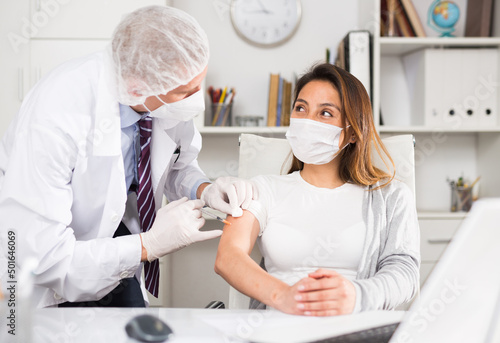 Male doctor giving vaccine to woman in company office