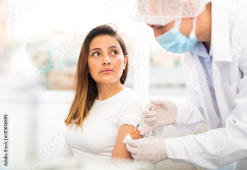 Health care concept, doctor in protective face mask vaccinates woman against coronavirus at vaccination center