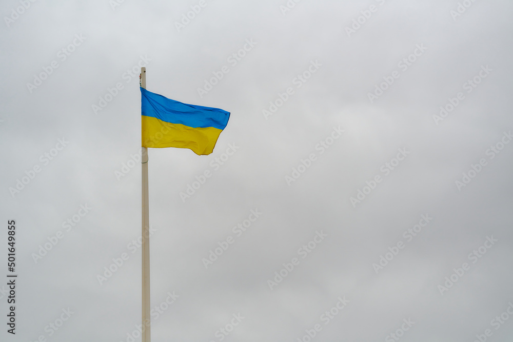 waving flag of ukraine on white flagpole over dark sky waving flag of ukraine on white flagpole over dark sky