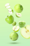 Ripe flying apples and halves on green background