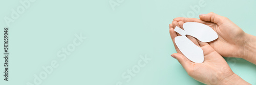 Female hands holding paper lungs on light blue background with space for text