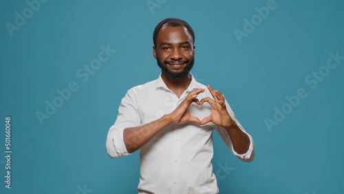 Emotional adult doing heart shape symbol with hands, advertising romantic affectionate sign to express love, gratitude and feelings. Happy smiling man showing romance gesture on valentines day.