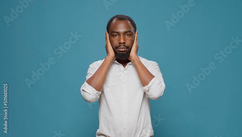 African american man doing three wise monkeys symbol, covering eyes, mouth and ears to keep secret and not find out confidential information. Young person respecting privacy and secrecy.