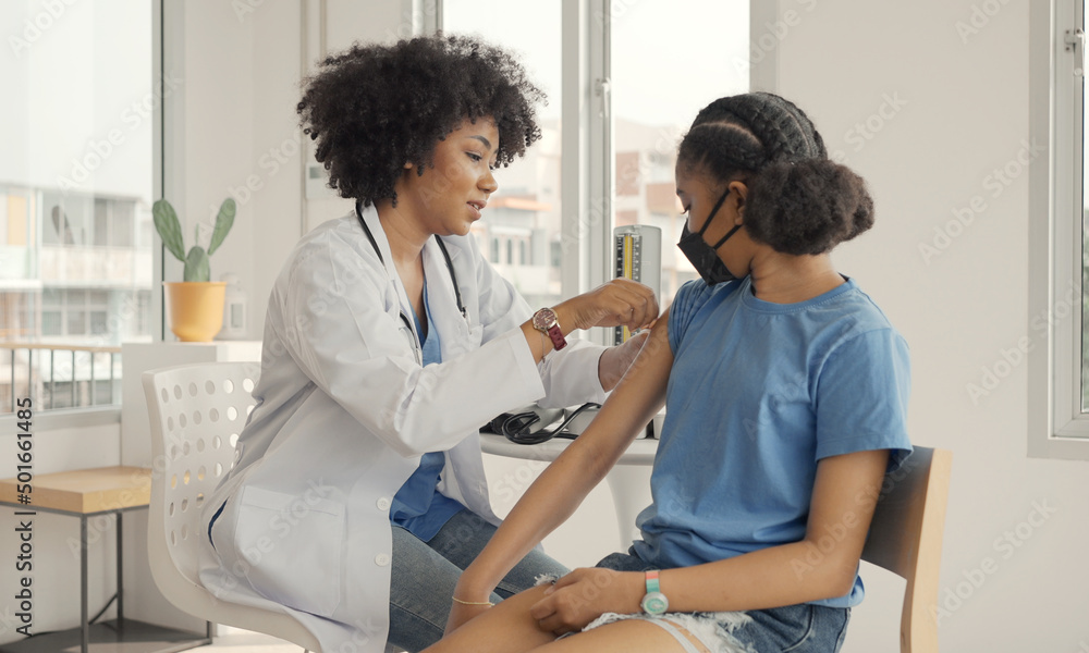 Fototapeta premium African american doctor is applying plaster to a child's shoulder after being vaccinated. 