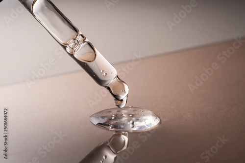 Pipette with serum, gel, oil or other cosmetic product on a beige background.