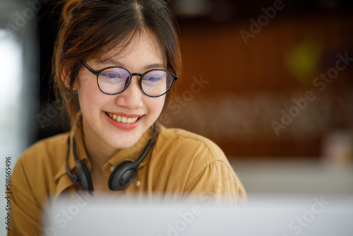 Student learning on laptop indoors- educational course or training, seminar, education online concept, Asian woman with modern laptop and headphones learning at home 
