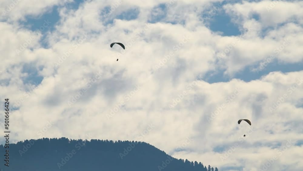 Closeup shot of parachutes in front of clouds and mountains. Adventure enthusiast doing paragliding in the sky. Adventure activities in Manali, Himachal Pradesh, India. Tourists enjoying adventure. Closeup shot of parachutes in front of clouds and mountains. Adventure enthusiast doing paragliding in the sky. Adventure activities in Manali, Himachal Pradesh, India. Tourists enjoying adventure.