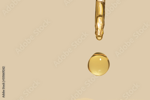 detail of gold pipette dropper with beauty serum on a beige background