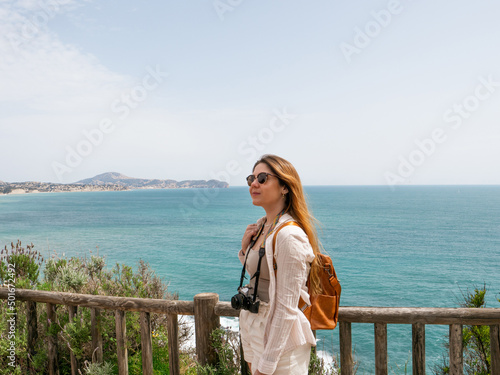 tourist woman with a camera with the sea on the background