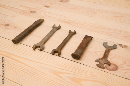 Rusty old open end wrenches, chiselson a wooden background