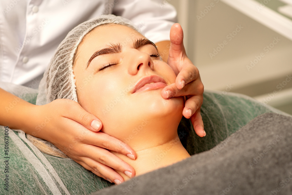 Face massage. Beautiful caucasian young white woman having a facial massage with closed eyes in a spa salon Face massage. Beautiful caucasian young white woman having a facial massage with closed eyes in a spa salon