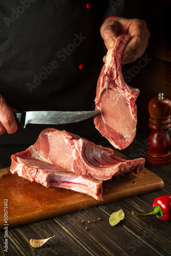 A professional chef cuts raw ribs on a cutting board before baking. Asian cuisine. Cooking delicious food in the kitchen