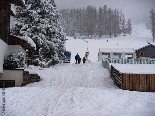 People Returning after a Day of Skiing at the end of the Ski Slope near the Houses