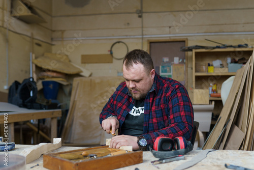 carpenter in a plaid shirt working with wood in the workshop