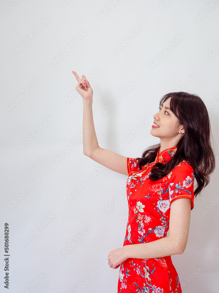 Asian woman wearing traditional cheongsam qipao dress hand pointing up to copy space isolated on white background. Asian woman wearing traditional cheongsam qipao dress hand pointing up to copy space isolated on white background.