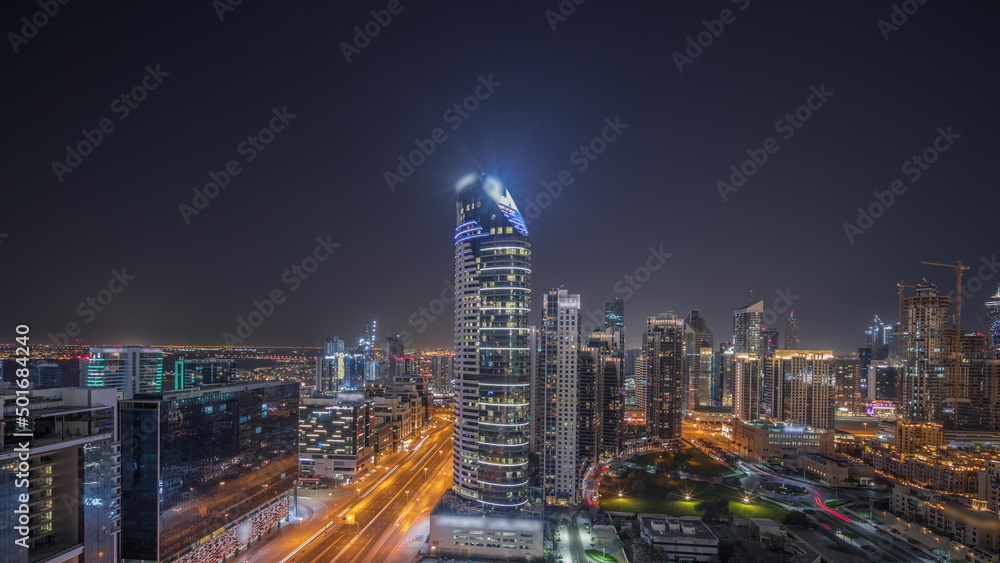 Panorama showing Dubai's business bay towers aerial night timelapse. Rooftop view of some skyscrapers