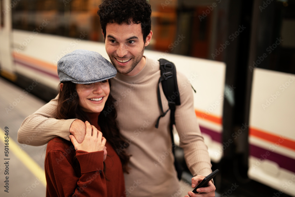 Beautiful couple at railway station waiting for the train. Young woman and man waiting to board a train....