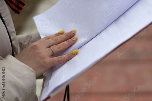 The secretary holds a tablet with papers. The girl is holding an office paper with text.