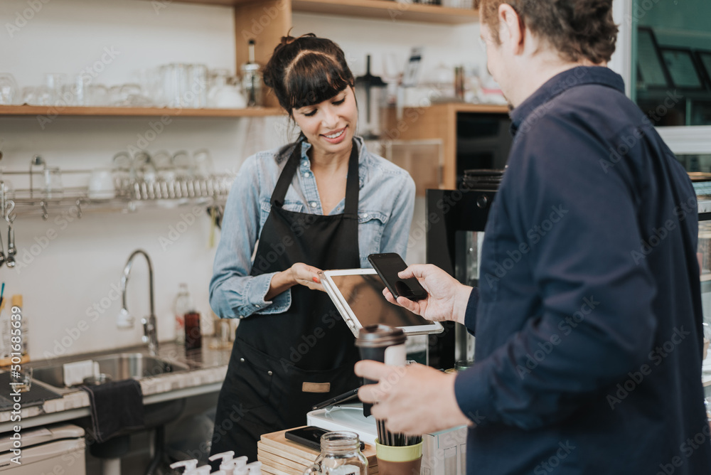 Obraz premium Caucasian woman barista take order from customer in coffee shop. female barista using digital tablet to take order. Coffee owner concept.