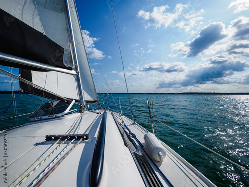 view on a sailboat bow of white sailing yacht on a lake during sailing in a summer sunny day © lenaivanova2311