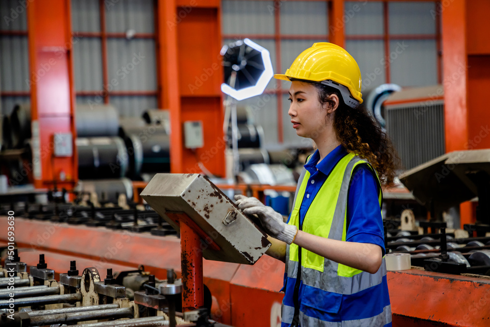 Factory women workers in safety suits and helmets control machines in the production line plant metal, industry heavy metal. Factory women workers in safety suits and helmets control machines in the production line plant metal, industry heavy metal.