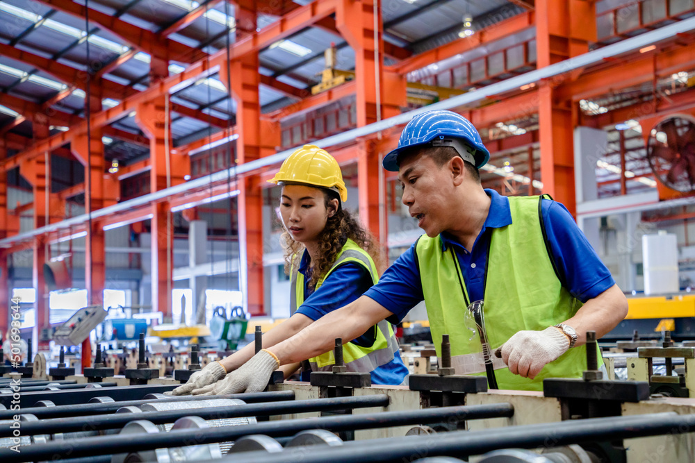 Factory manager or supervisor in safety suit and helmet discussing workshop in the production line plant metal, Working together, Coordination and Teamwork concept. Factory manager or supervisor in safety suit and helmet discussing workshop in the production line plant metal, Working together, Coordination and Teamwork concept.