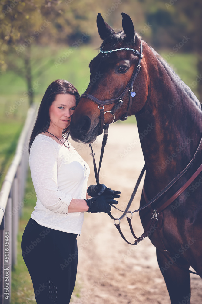 Obraz premium Woman with horse, horse and woman stand next to each other and the woman nestles her head against the horse's nose..