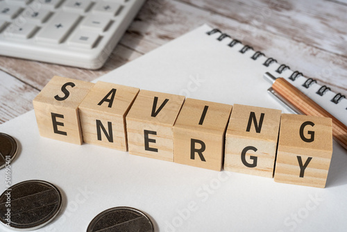 省エネのイメージ「SAVING ENERGY」と書かれた積み木、電卓、ノート、コイン、ペン