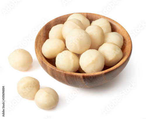 Shelled Macadamia nuts in the wooden bowl, isolated on white background.