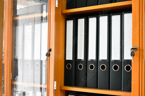 An office file cabinet that holds a large number of binders in an office, soft and selective focus on document binders. photo