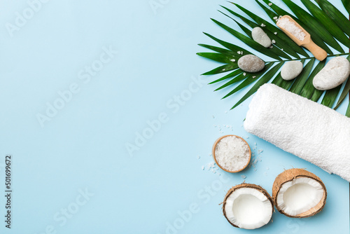 Coconut with jars of coconut oil and cosmetic cream on colored background. Top view. Free space for your text. Natural spa coconut cosmetics and organic treatment concept Coconut Spa composition