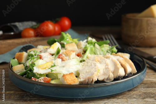 Delicious Caesar salad in bowl on wooden table