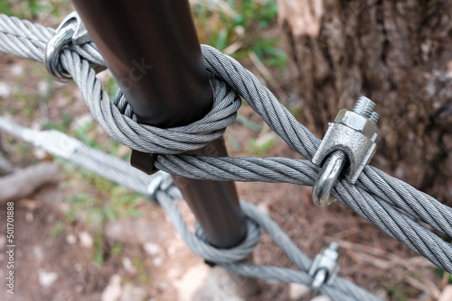Interlocking steel cable secures a barrier on a mountain path.