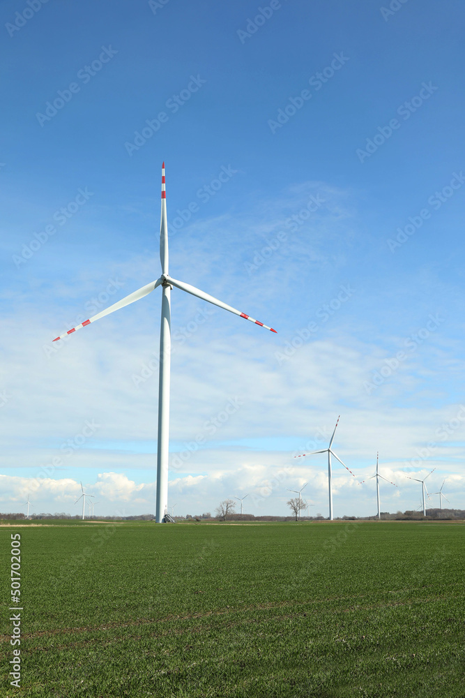 Modern wind turbines in field on sunny day. Alternative energy source Modern wind turbines in field on sunny day. Alternative energy source